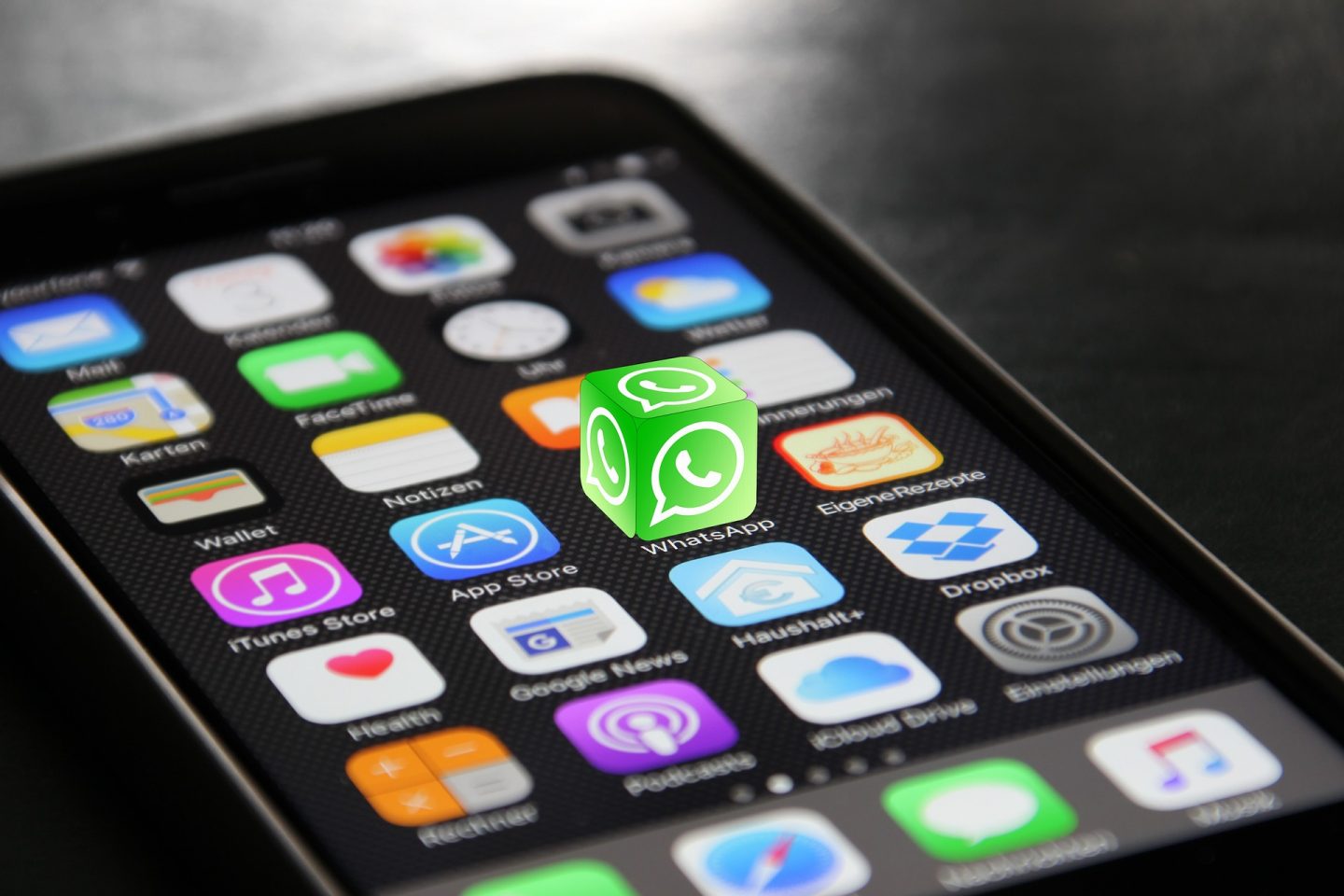 A phone showing an array of apps. The Whatsapp icon looks 3D and stands out of the phone