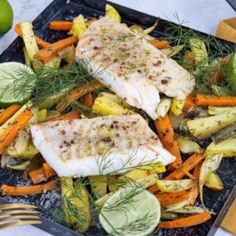 A baking tray with roasted vegetables and fish on it
