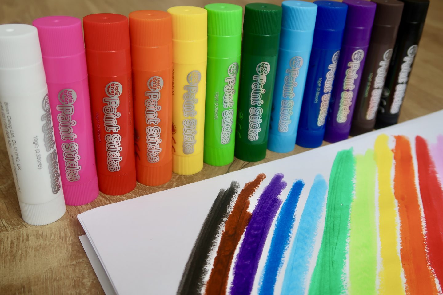 a rainbow painted on a piece of paper, with paint sticks lined up behind it in all the colours