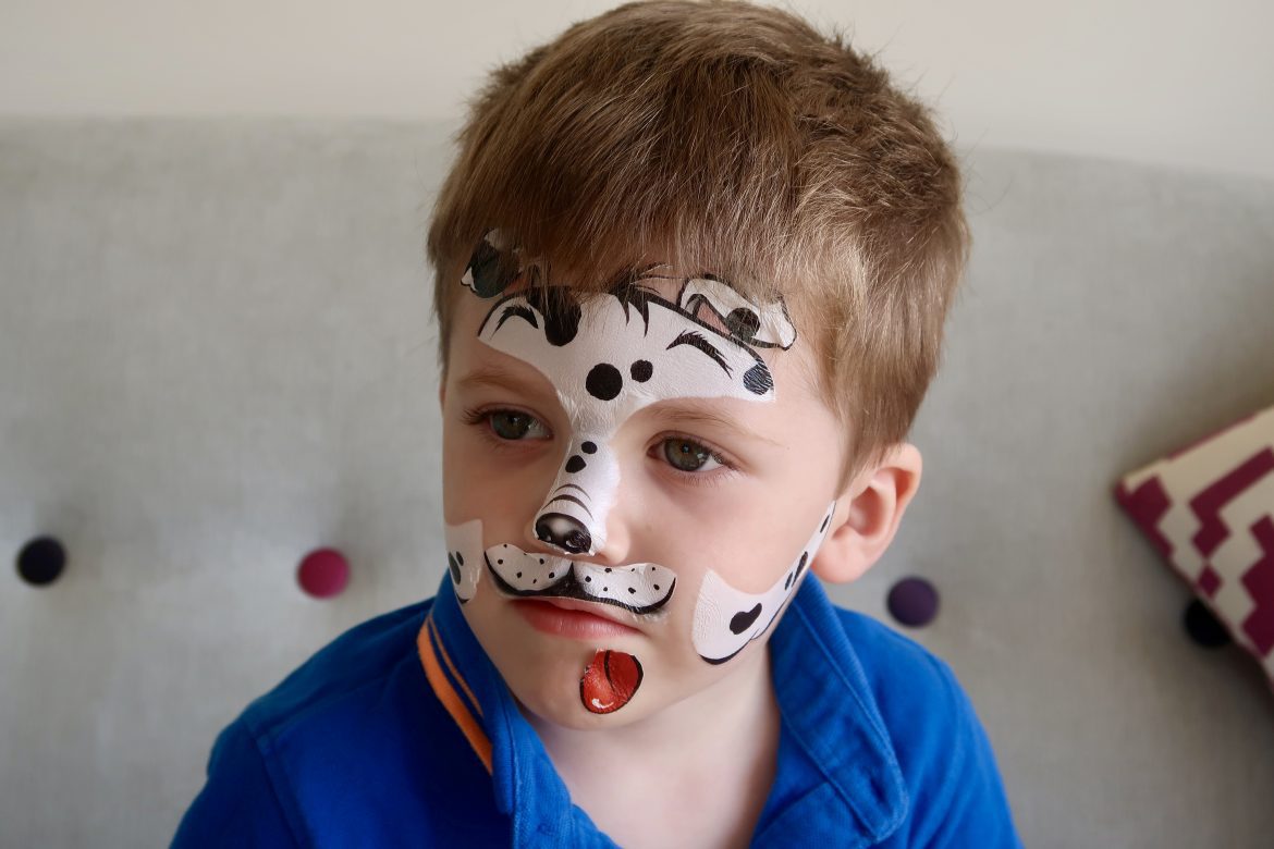 A boy with his face painted like a dog