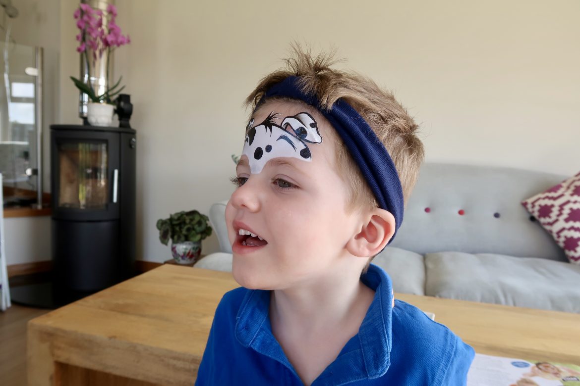 A boy having his face paints done to look like a dalmation