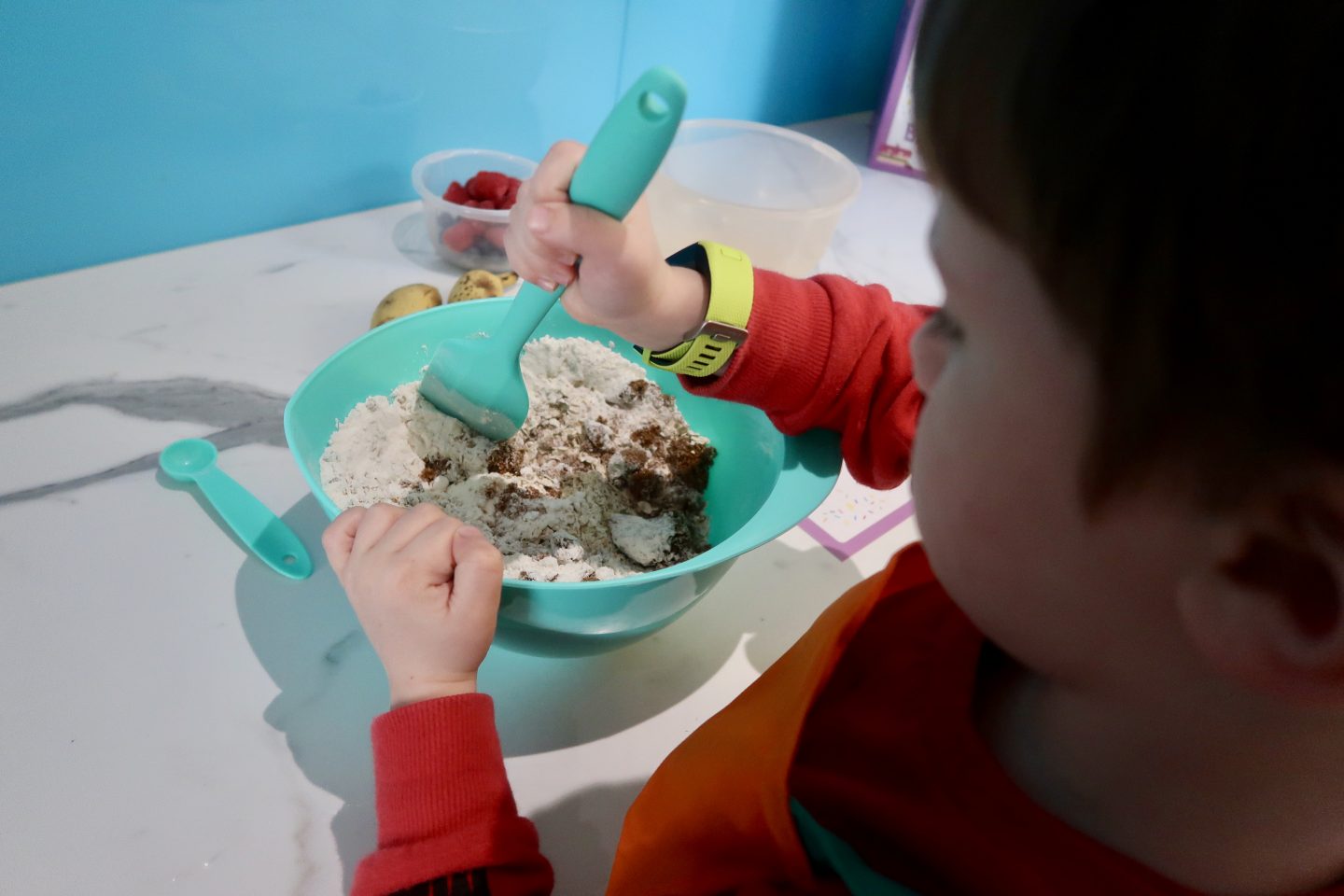 A child stirring a green mixing bowl