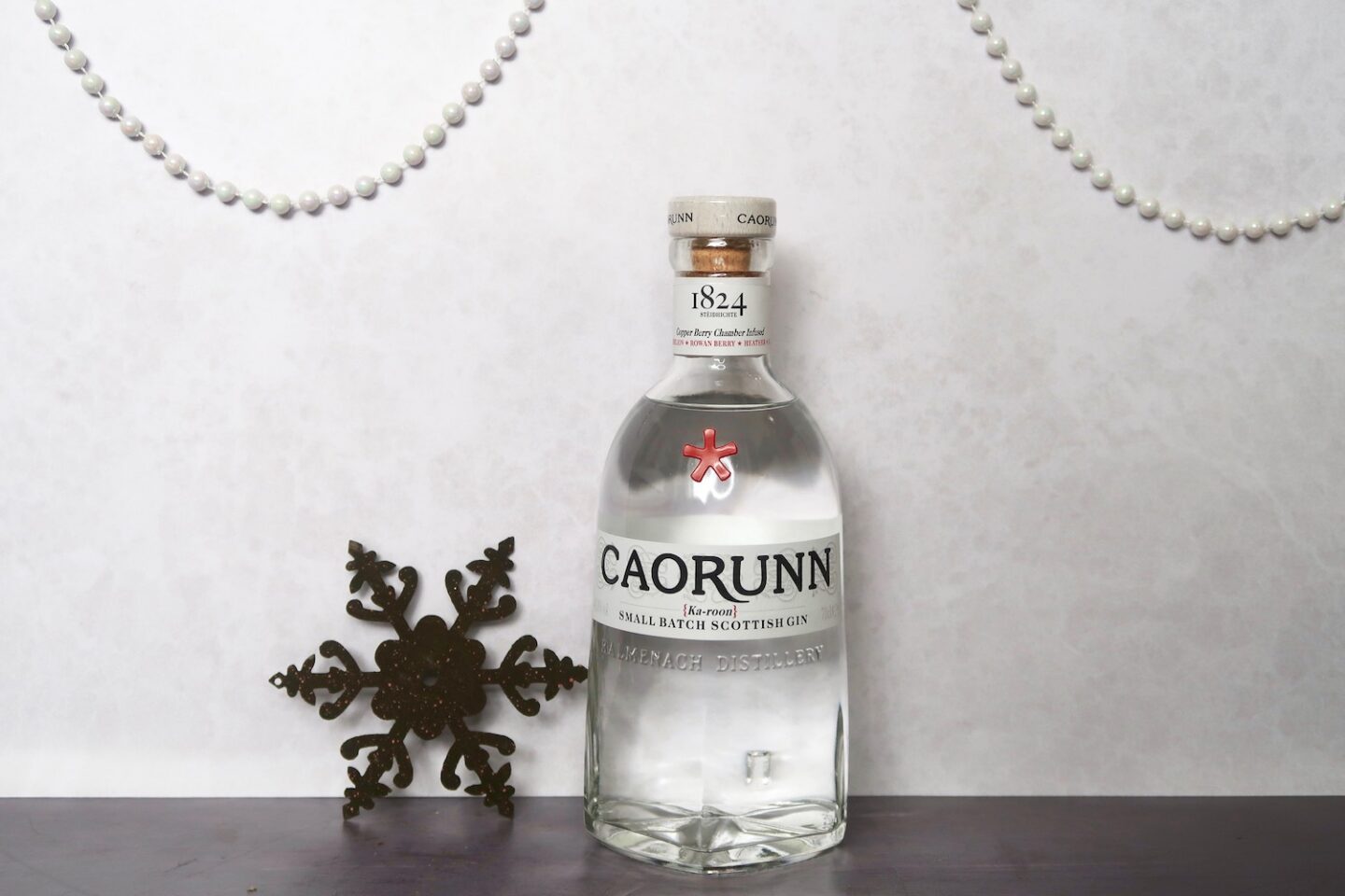 A bottle of Caorunn gin next to a metal snowflake