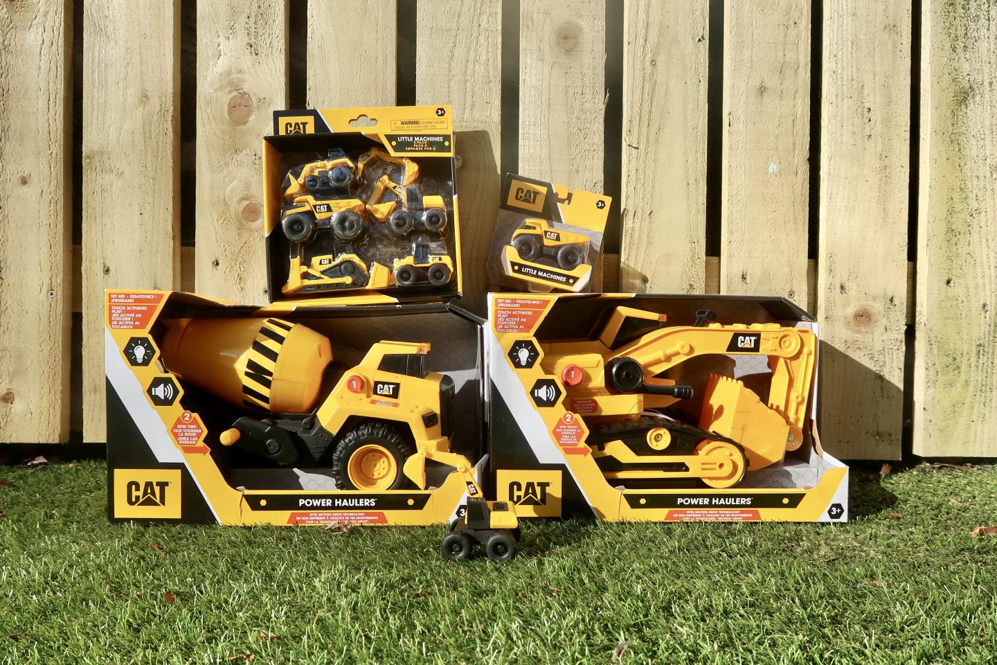 Cat construction toys stacked up on the grass against a fence