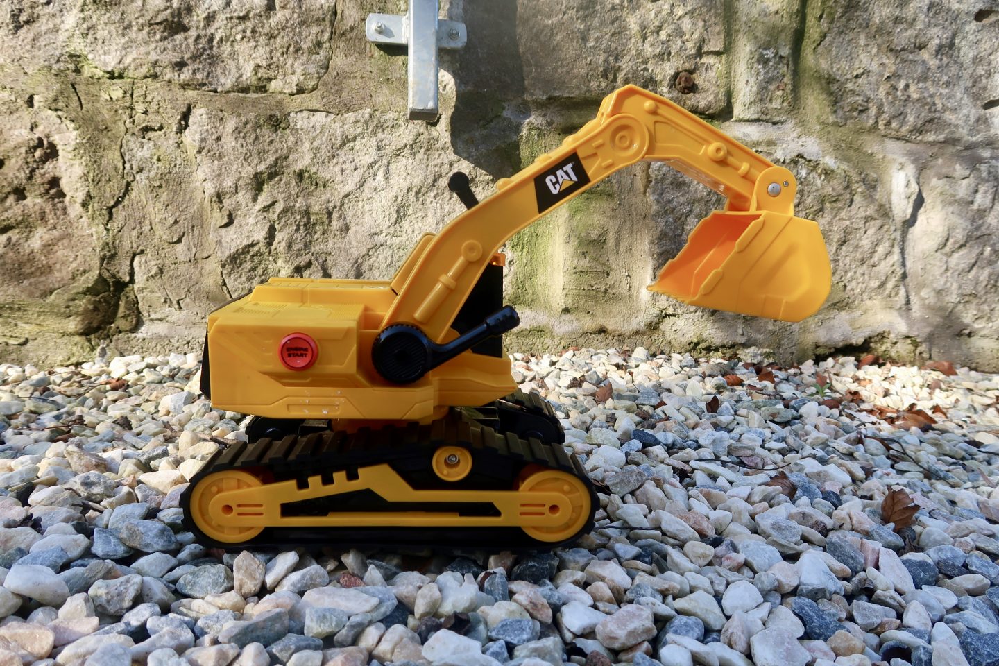 A toy digger sitting on some stones