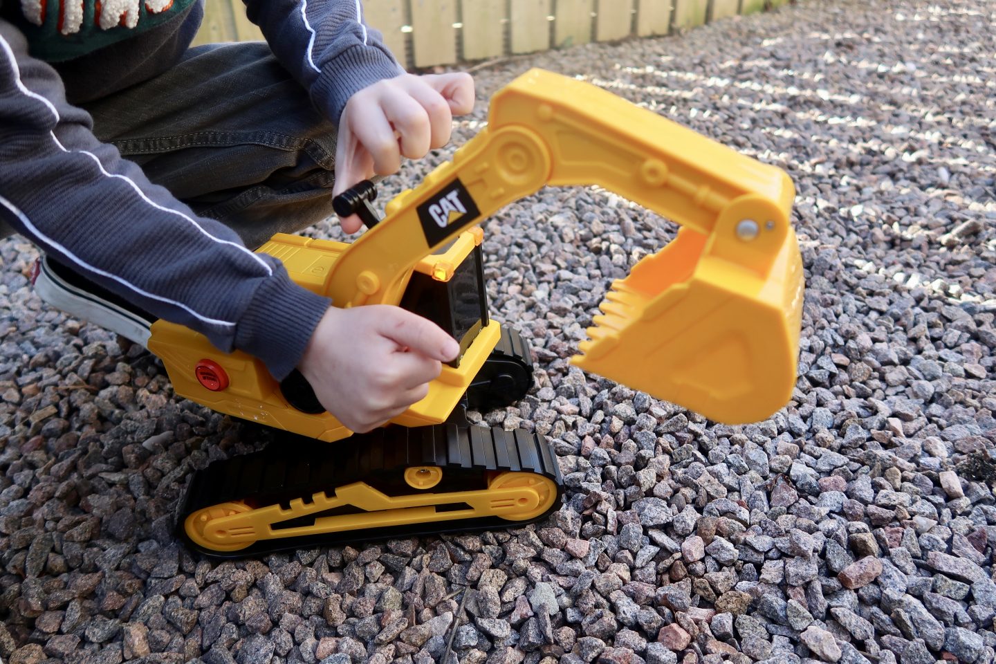 A yellow toy digger being moved by a childs hands
