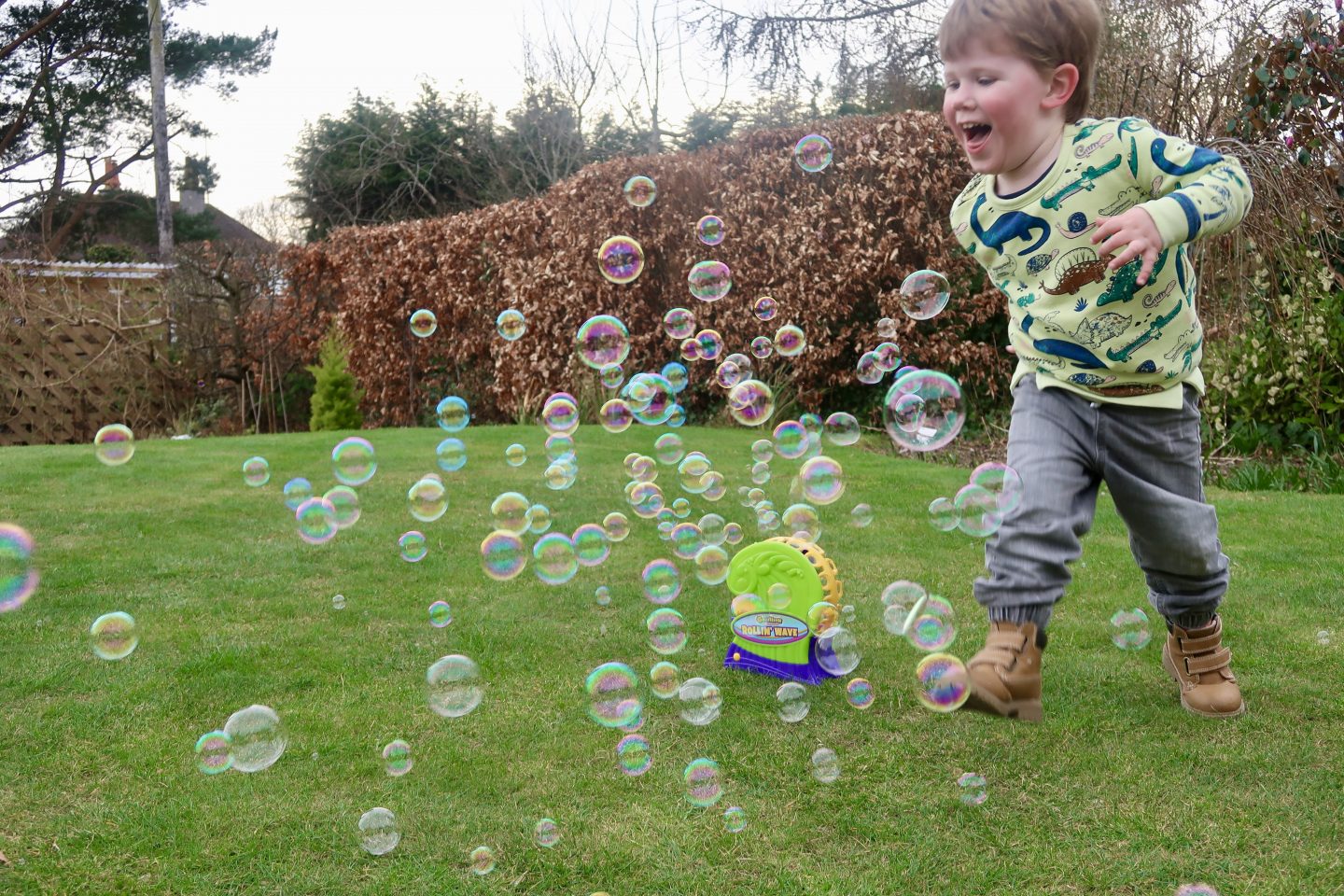 A little boy running through bubbles coming out of a bubble machine