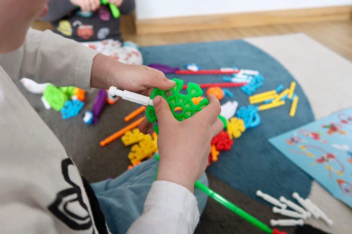 A child's hands holding some green Kid K'Nex connectors