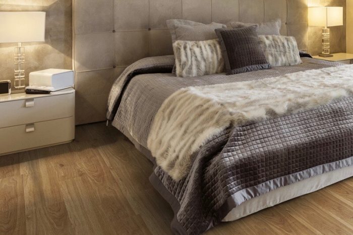 A cosy bedroom with neutral colours on the bedding and the side lights giving a warm glow