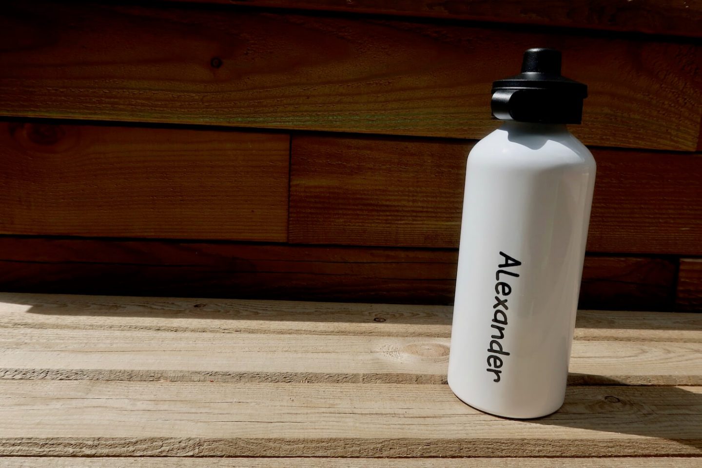 A wooden bench with a white kids water bottle on it