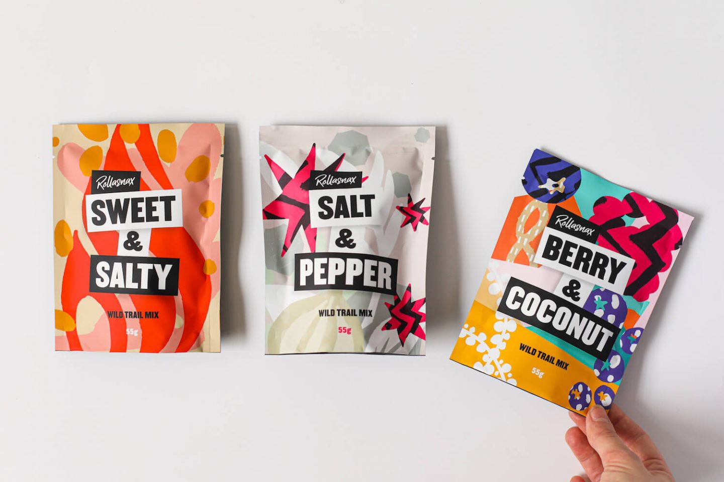 3 packs of trail mix, with a hand grabbing one of the packs