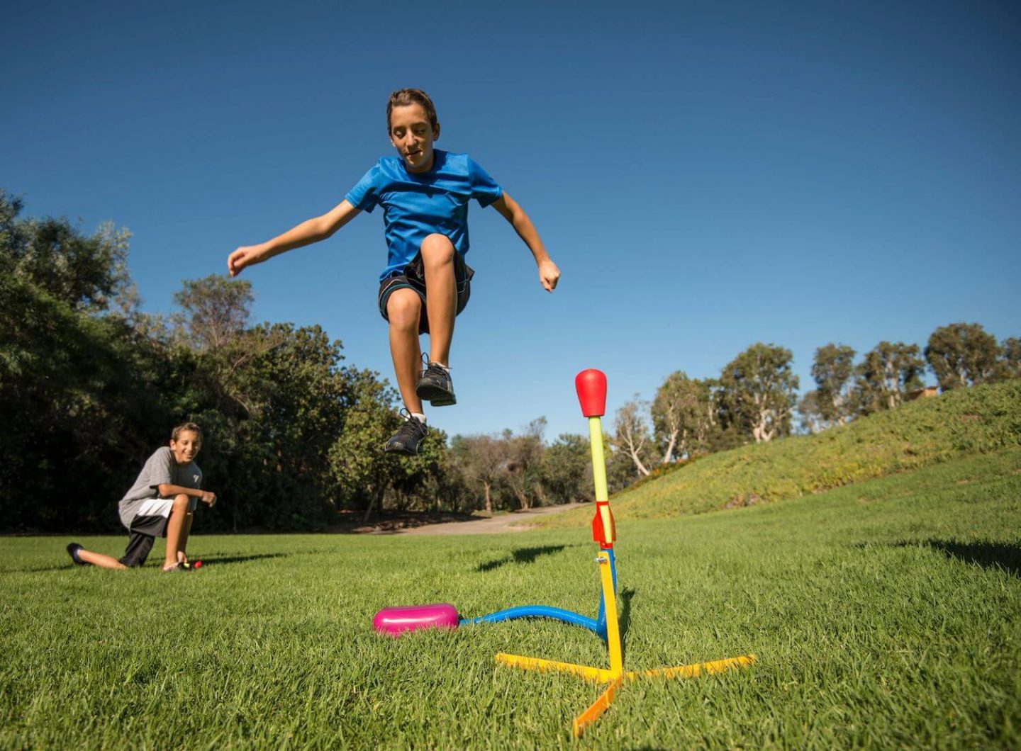 2 children playing with a stomp rocket toy in a field
