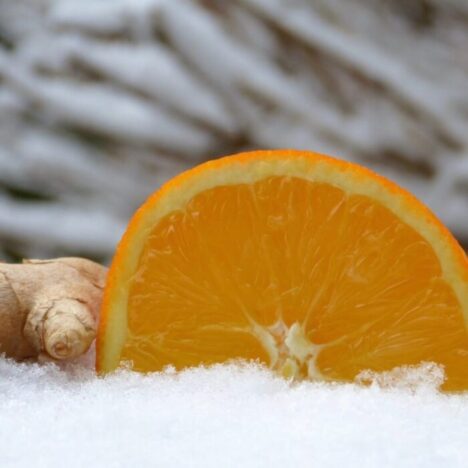 A sliced orange next to a piece of ginger