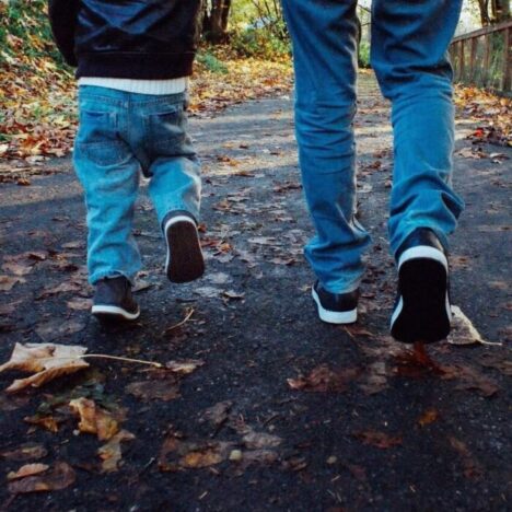 The legs of an adult and a child walking away, both wearing jeans