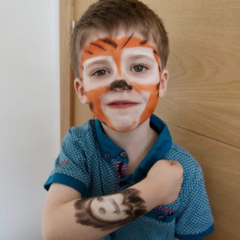 A young boy with his face painted like a tiger