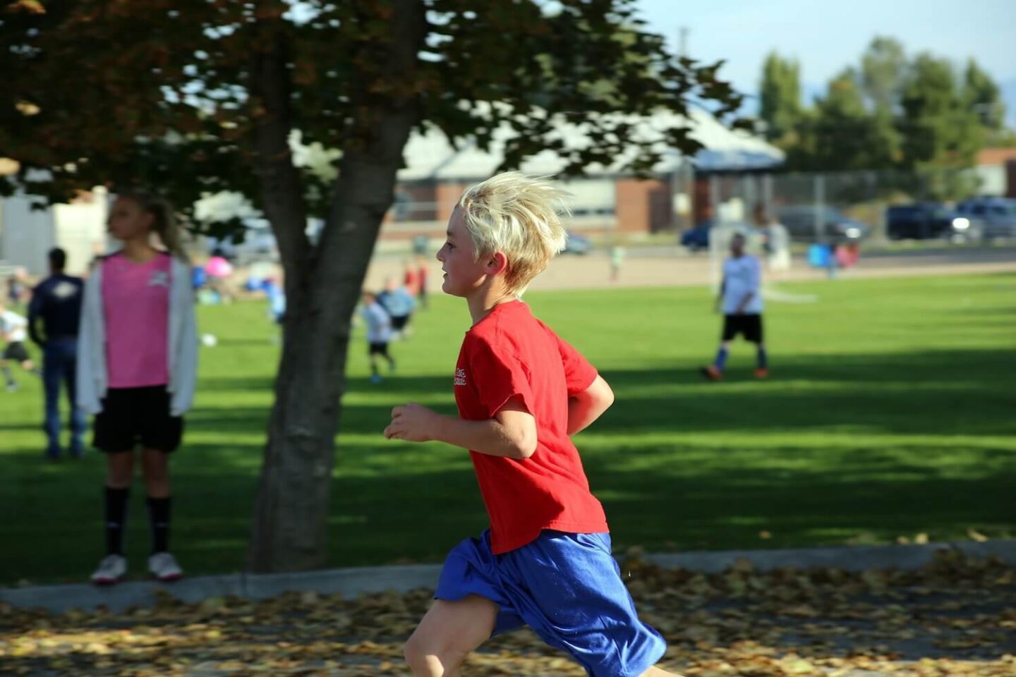 A boy running past a tree in a park