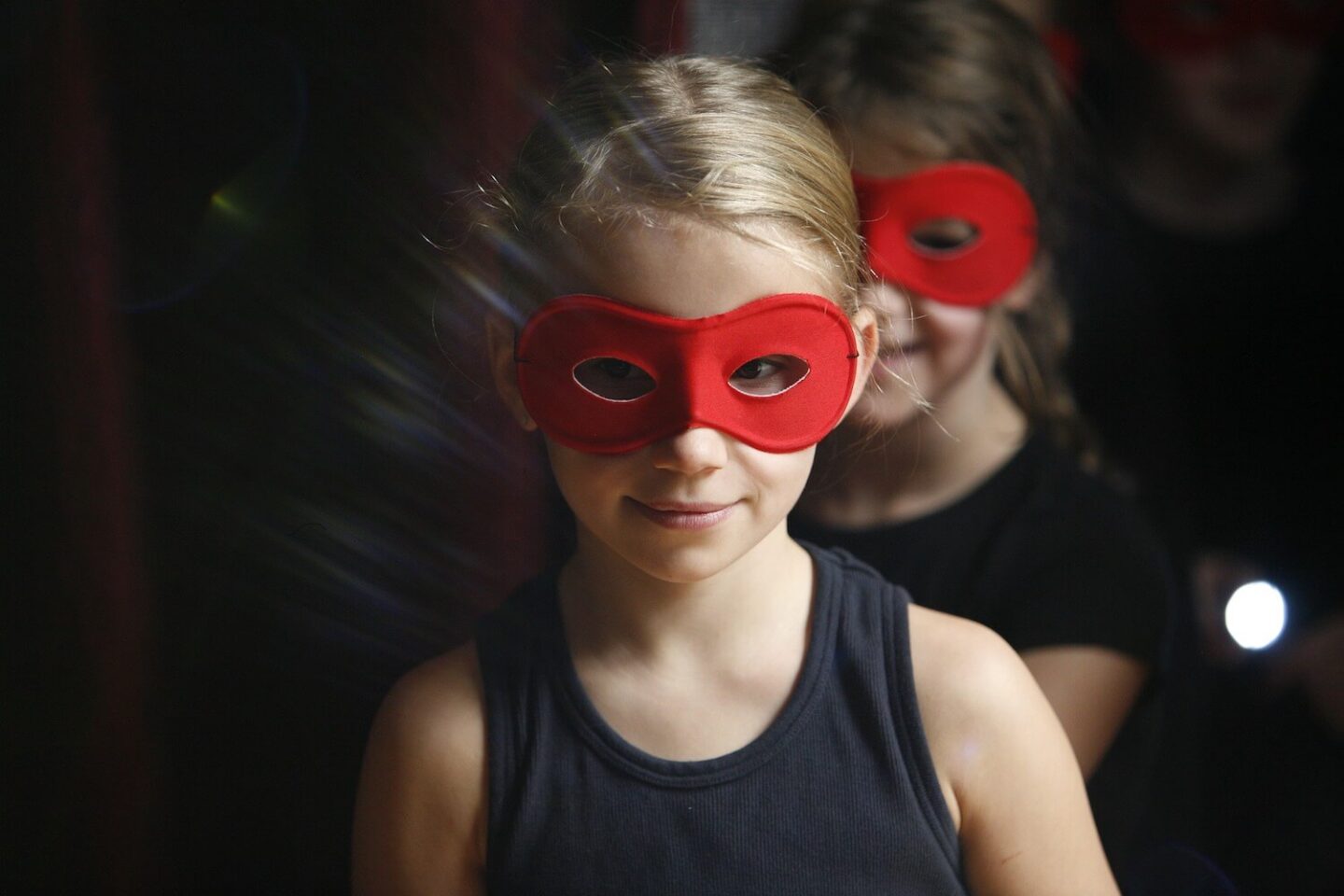 A girl in a black top and a red mask