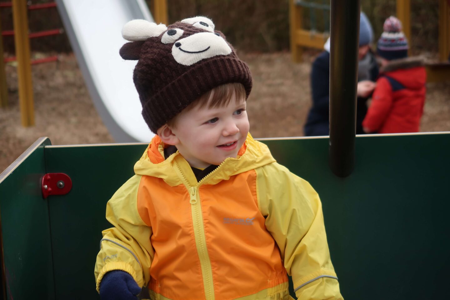 A young boy wearing a yellow puddle suit and a cow hat