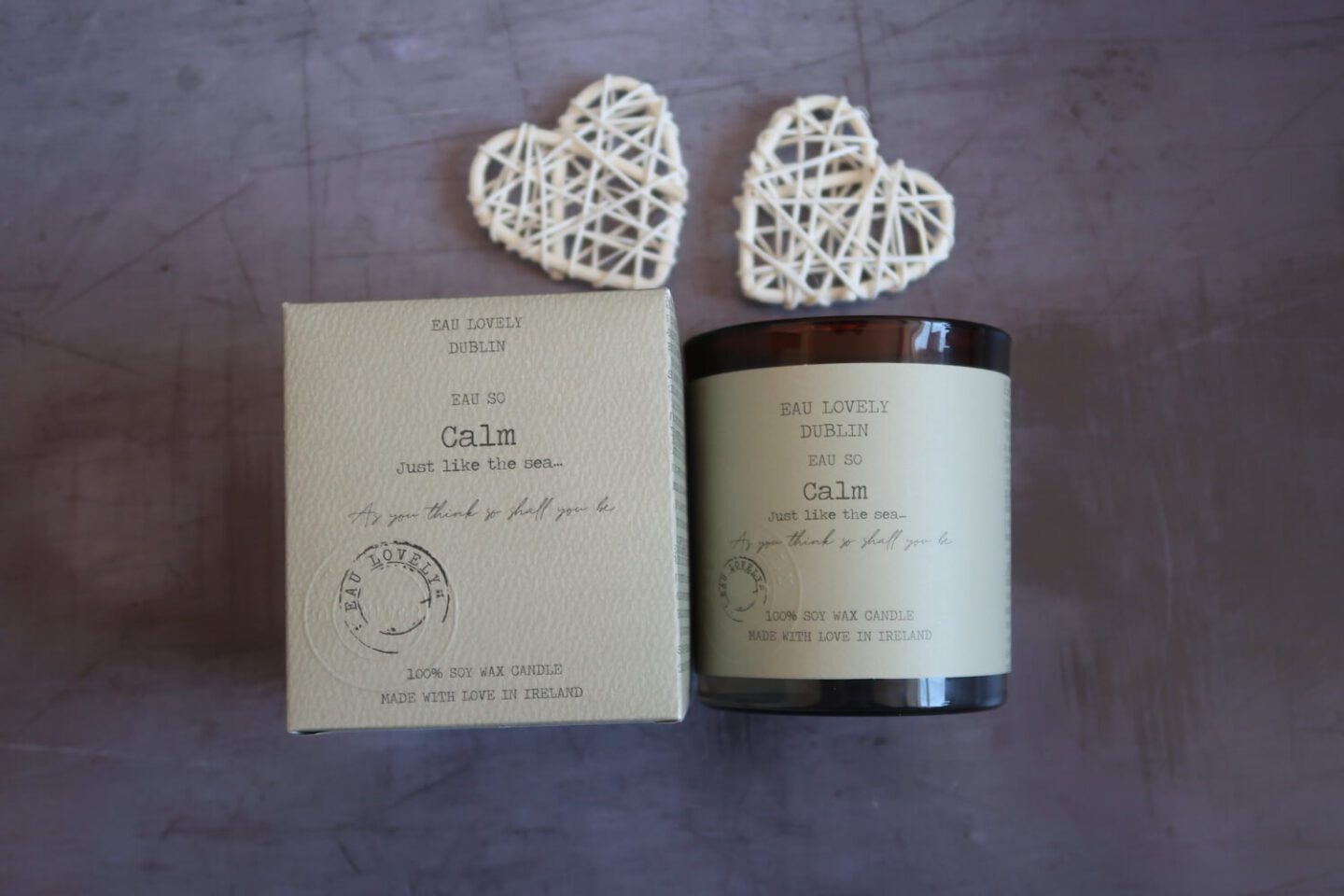 A Candle in a brown glass next to the packaging