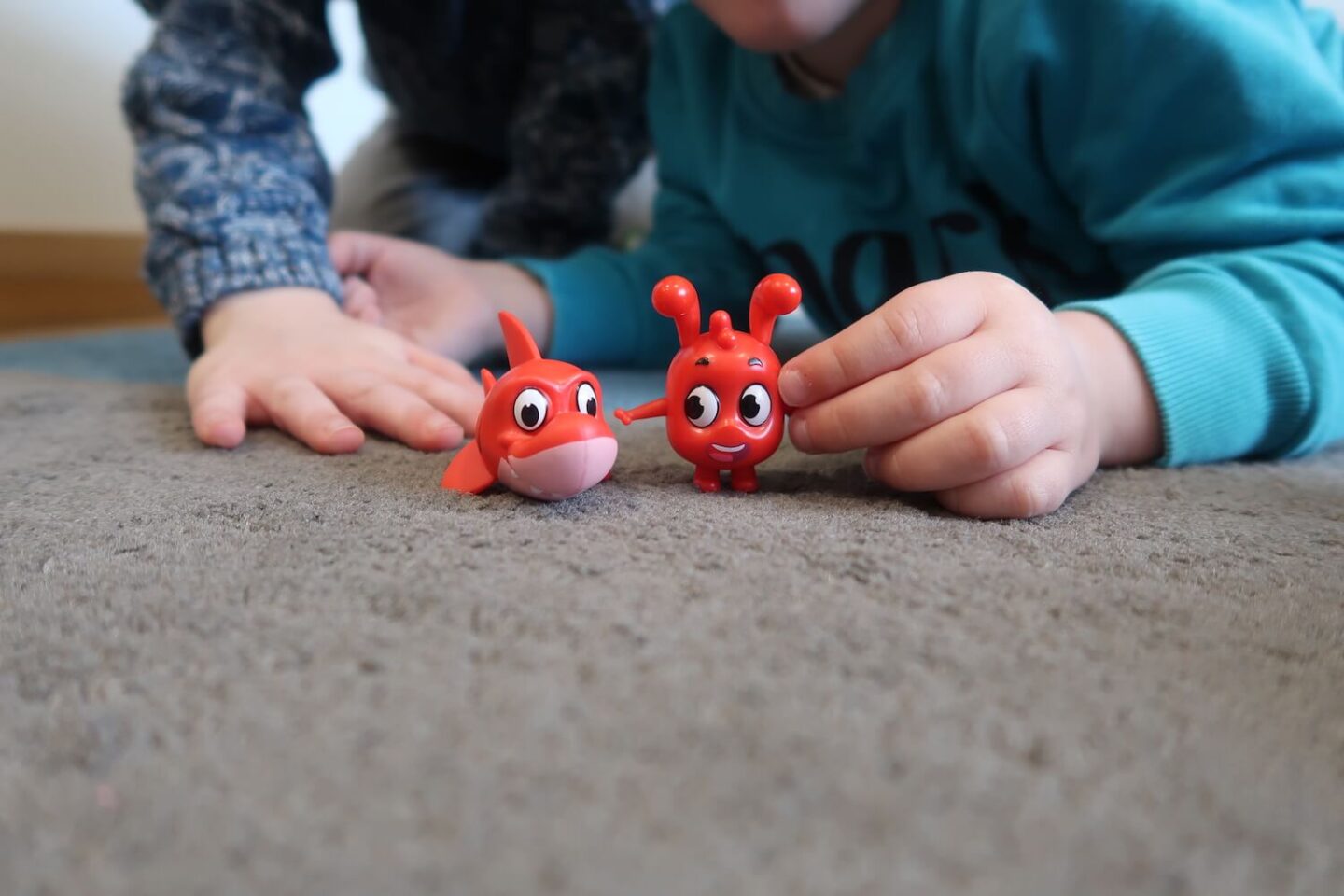 A Morphle toy and a Morphle shark toy being held by young children's hands