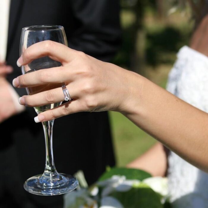 A brides hand holding a champagne glass