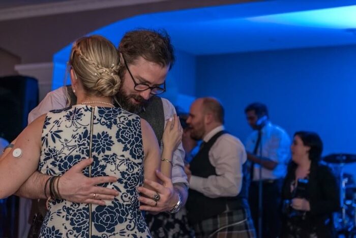 A man and woman hold each other on the dance floor at a wedding
