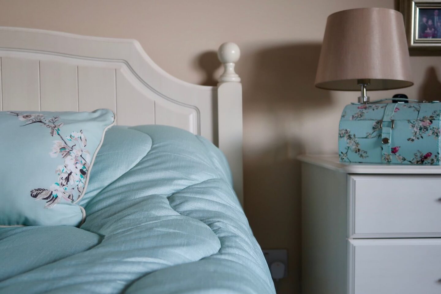 The side of a bed and a bedside table
