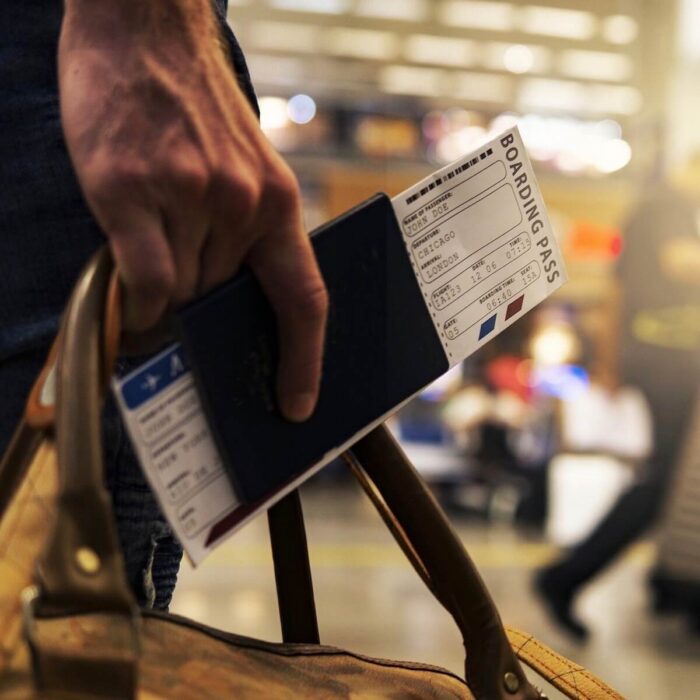 a hand holding a passport and boarding pass in an airport