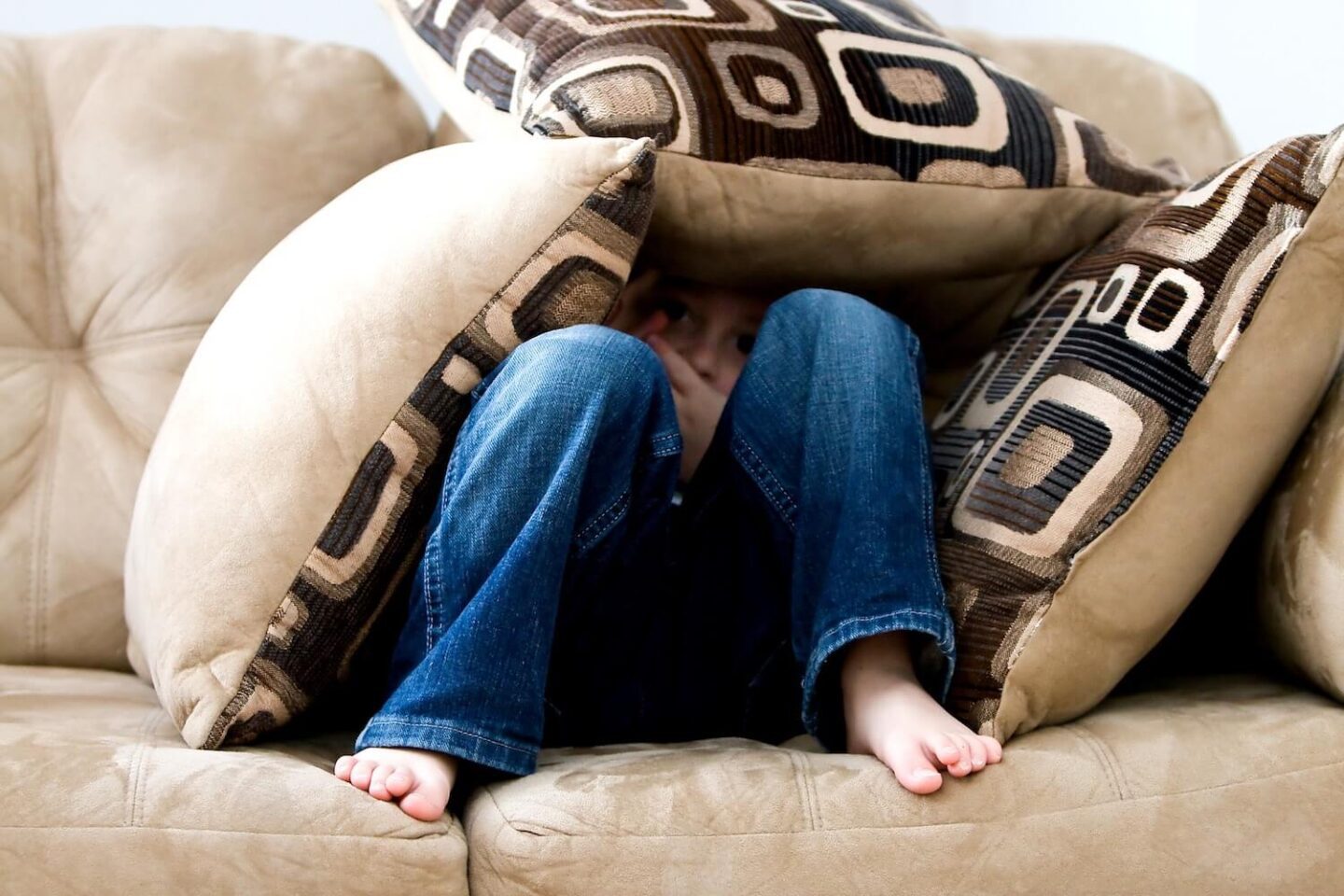 A child hiding under some sofa cushions