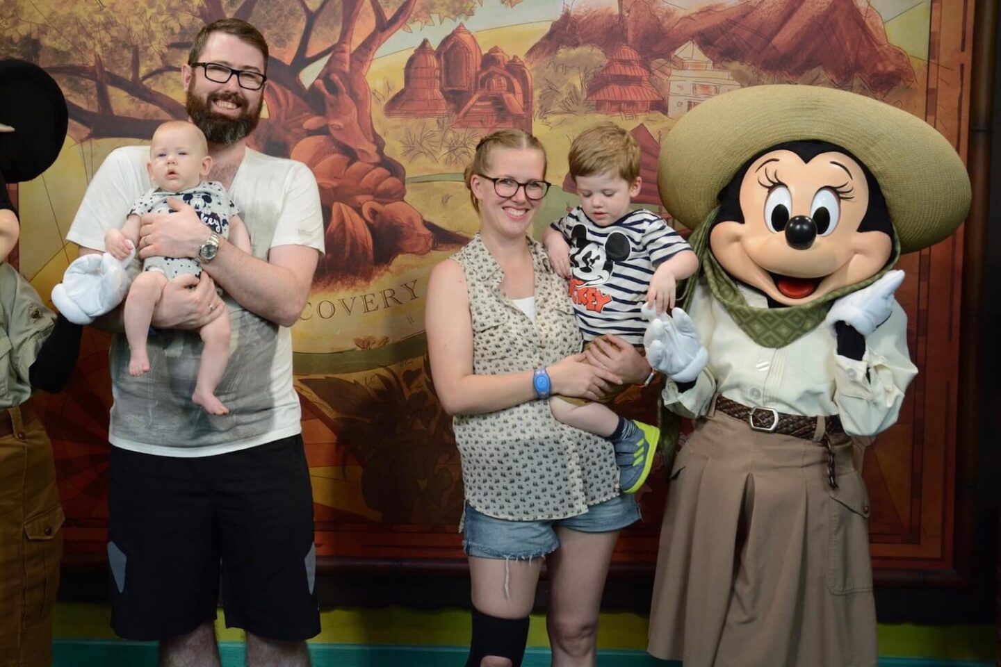 A family posing for a picture with Minnie Mouse. The woman has on shorts and a knee support.
