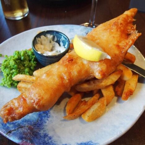 A plate of battered fish, chips and mushy peas