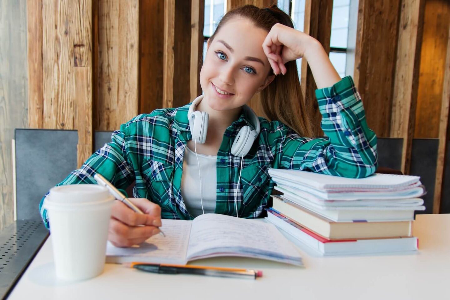 A teenager working at a table surrounded by books