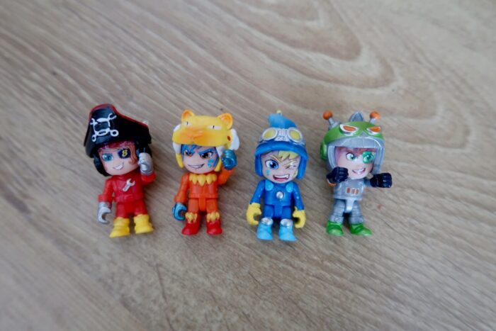 4 toy racing drivers lying on a wooden floor