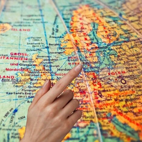 A woman's hand pointing to a country on a globe