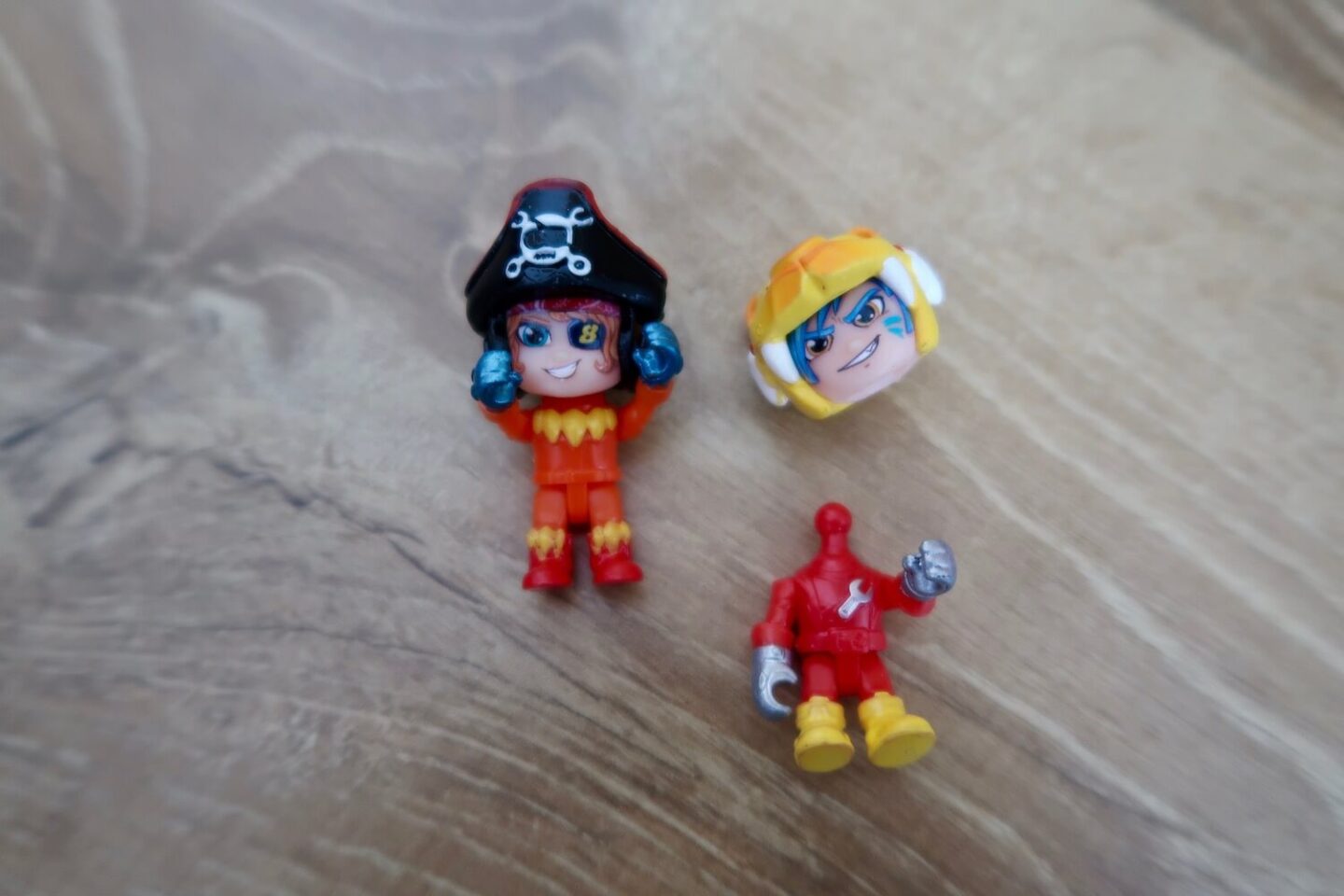 2 small plastic figures dressed as racing car drivers. The head has been removed from one of the toys