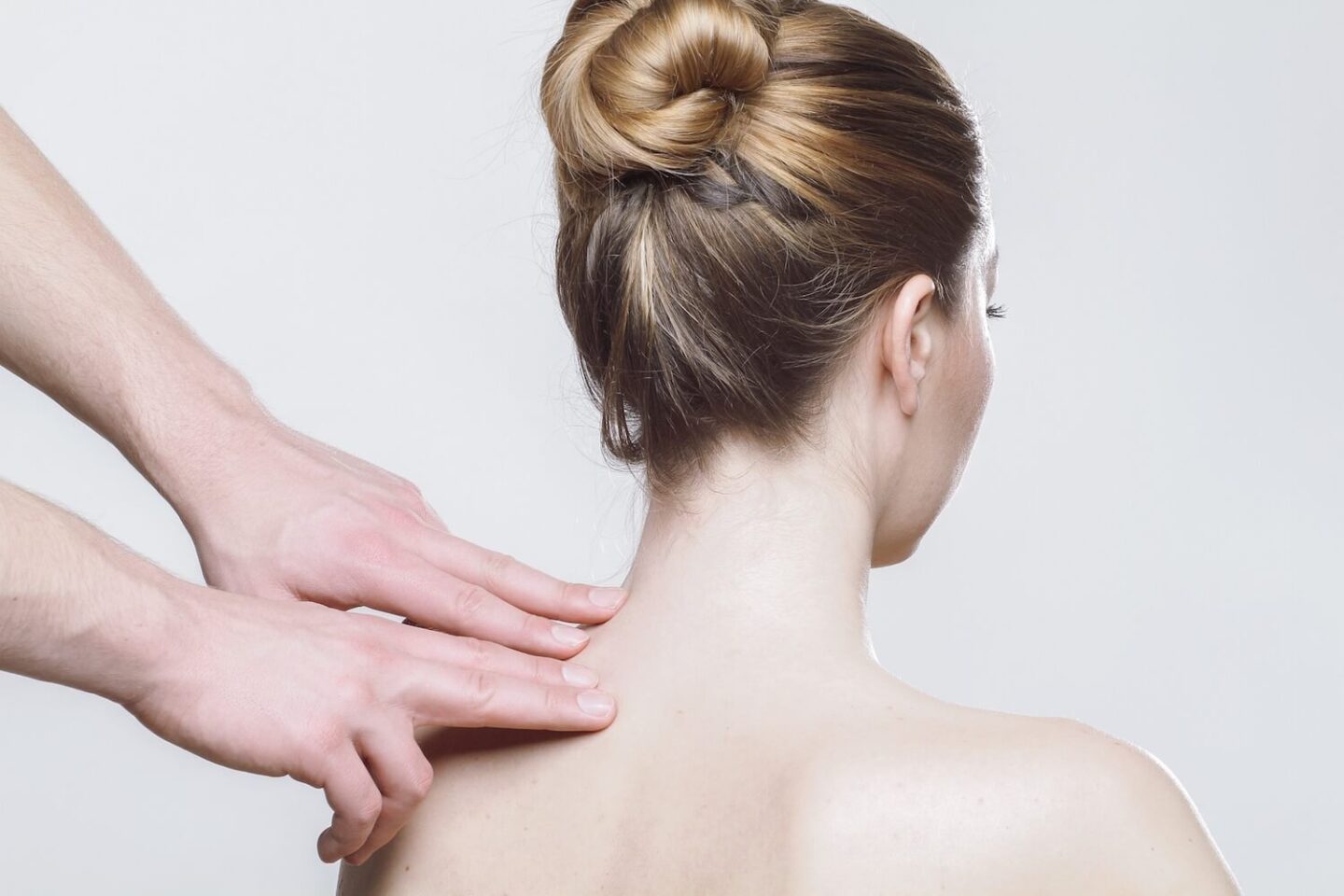 A woman sitting with bar shoulders while a mans hands rubs one of them
