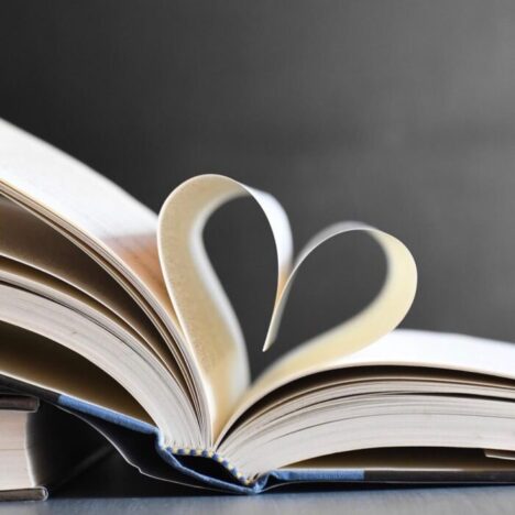A book open, with 2 pages folding down towards each other to make a heart