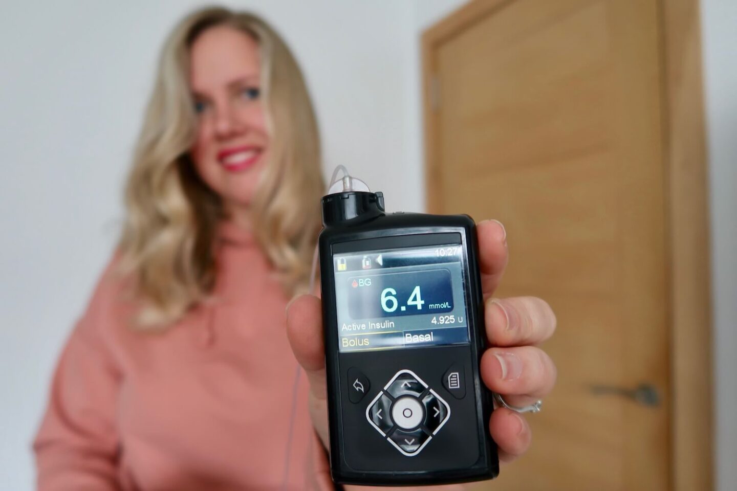 A blonde woman holding out a Medtronic insulin pump