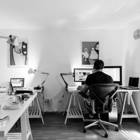 A black and white picture of a man working at a desk on a computer