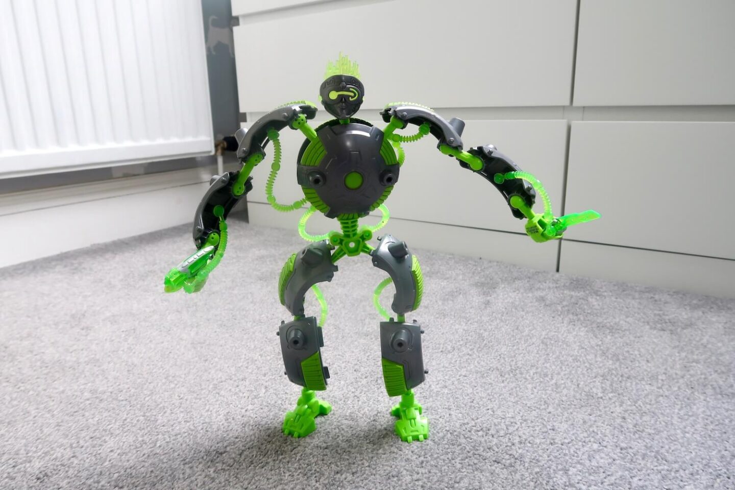 A Gigabot Fragbot transforming toy standing in a grey and white room.