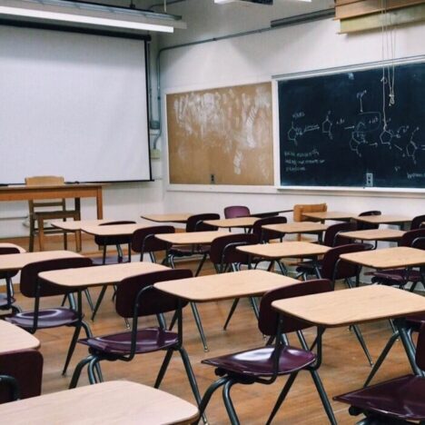 A classroom with lots of individual desks and a blackboard