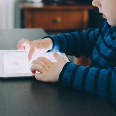 A child sitting at a table and playing on a tablet