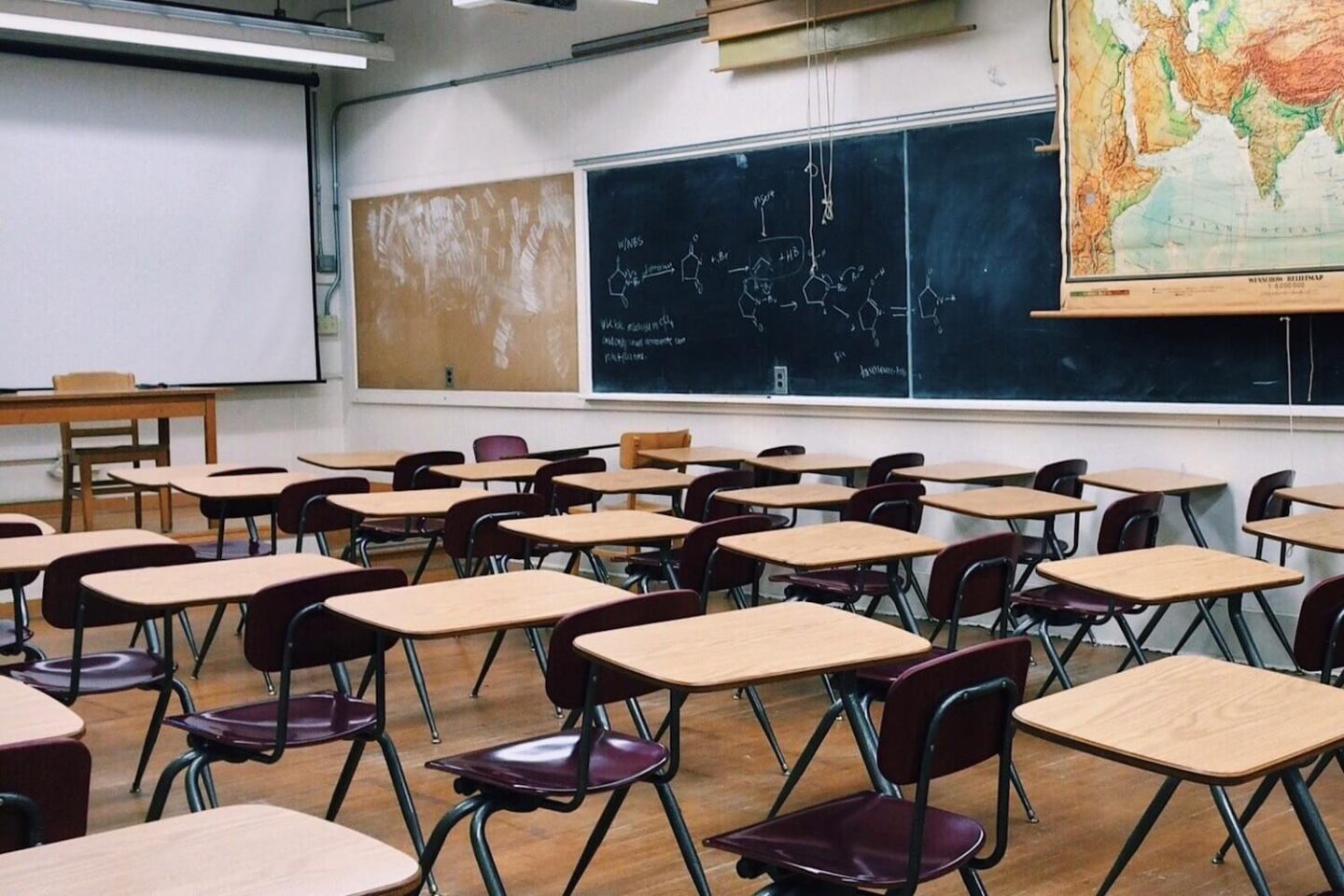 A classroom with lots of individual desks and a blackboard