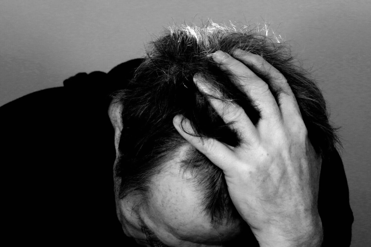 A black and white image of a man with his head in his hand