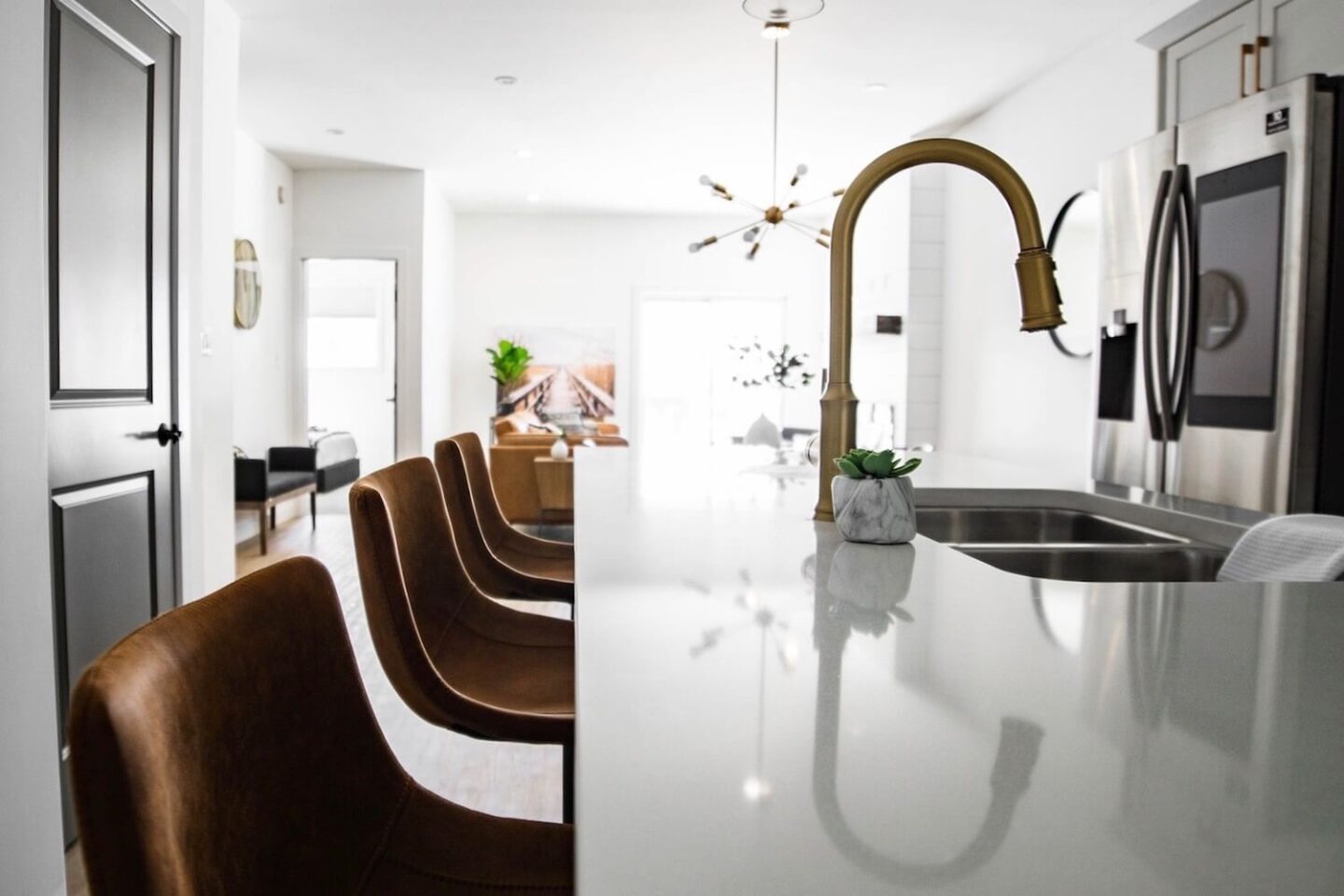 The breakfast bar in a kitchen. There are 3 high stools on one side and a sink on the other