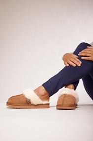 the legs of a person wearing tan coloured slippers with a fluffy white trim