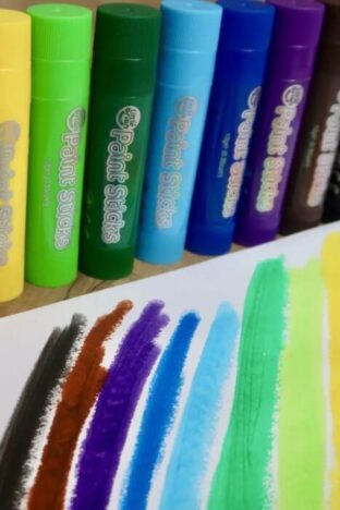a rainbow painted on a piece of paper, with paint sticks lined up behind it in all the colours