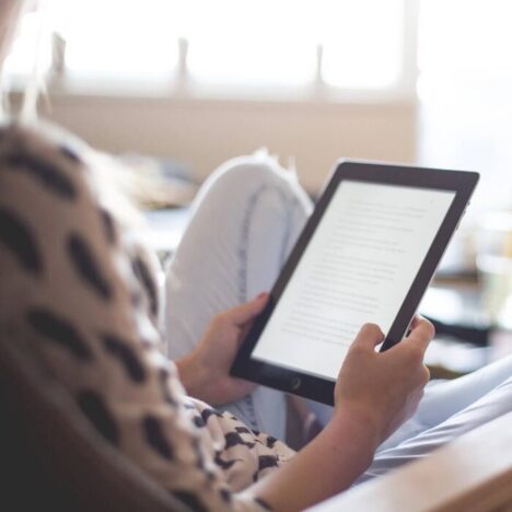 A Kindle being red by a person sat on a chair