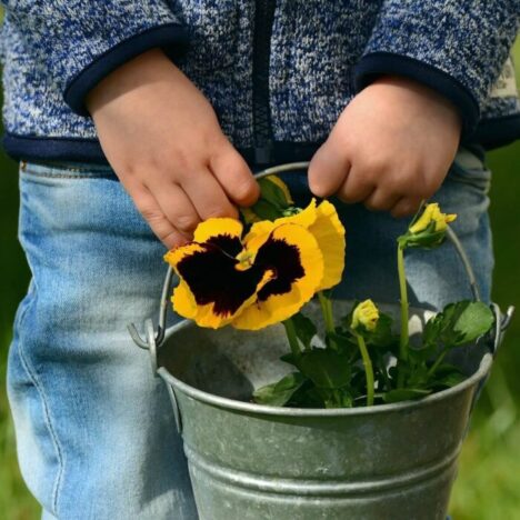 A child holding a metal bucket with a yellow flower on it