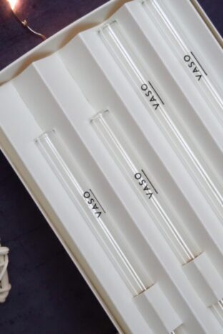 A pack of glass straws against a dark background with fairy lights